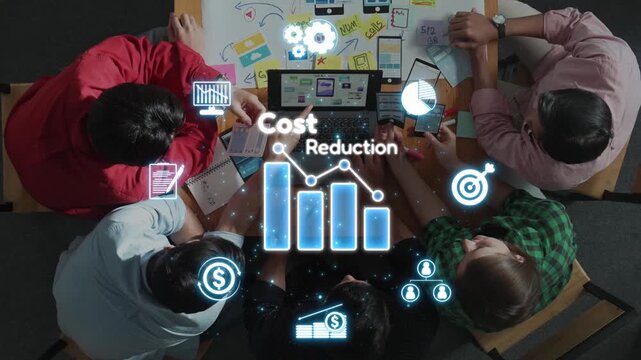 A dynamic business team collaborates on innovative cost reduction strategies. This overhead view captures analysis and brainstorming around financial concepts with visual elements. Raster