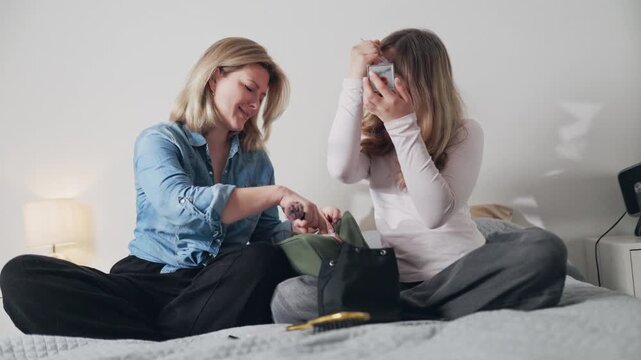 Two female friends preparing together on bed