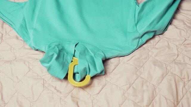 Decluttering process: Woman taking clothes on hangers out of wardrobe and putting them on a bed, top view,4k 10-bit footage.