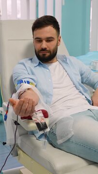 Young bearded man donating blood in a hospital clinic