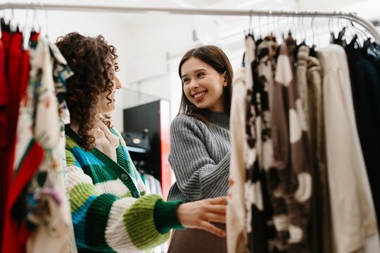 Happy women shopping clothes together in boutique store