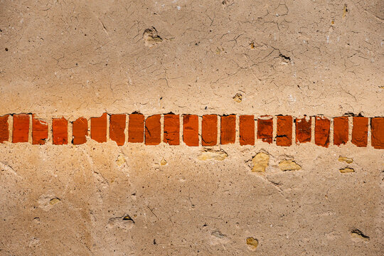 a single row of red bricks in a plastered wall