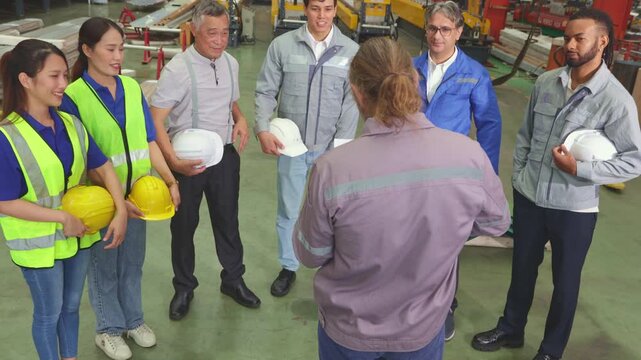Team workers stand meeting metal sheet factory personnel from various positions and roles present supervisor gives motivational speech before workers begin duties respective departments.
