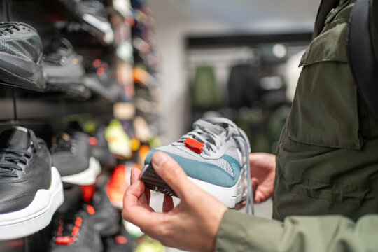 Sneaker shopping, customer choosing running shoes in sports store, footwear retail, consumer decision, active lifestyle, fashion purchase, product comparison.