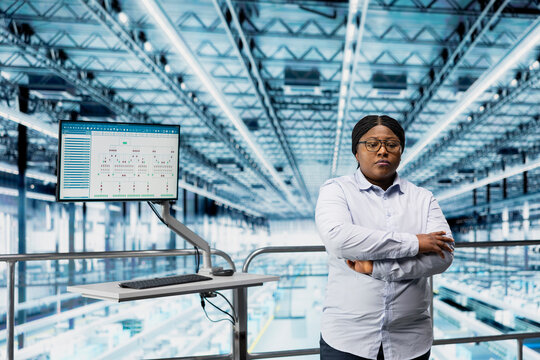 Woman in microchip smart factory using MES software to optimize production lines workflow. African american supervisor tracking semiconductor production hardware performance metrics