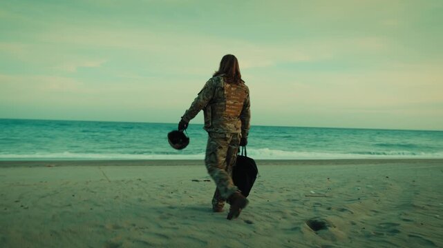 Soldier walks down beach toward ocean ready for rescue by dinghy