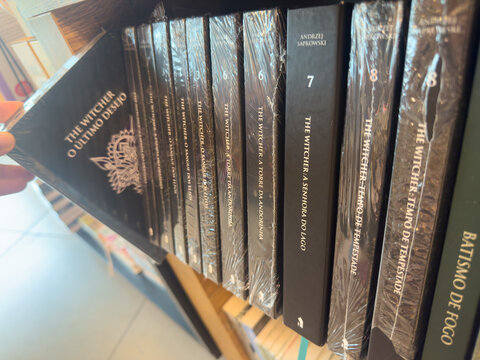 BELO HORIZONTE, MG, BRAZIL, MARCH 31, 2026. A person's hand is seen selecting "The Witcher: O &Uacute;ltimo Desejo" from a carefully organized shelf of the beloved series.