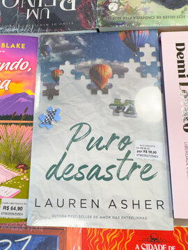 BELO HORIZONTE, MG, BRAZIL, MARCH 31, 2026. Hot air balloons and puzzle pieces adorn the charming blue and white cover of 'Puro desastre' by Lauren Asher.