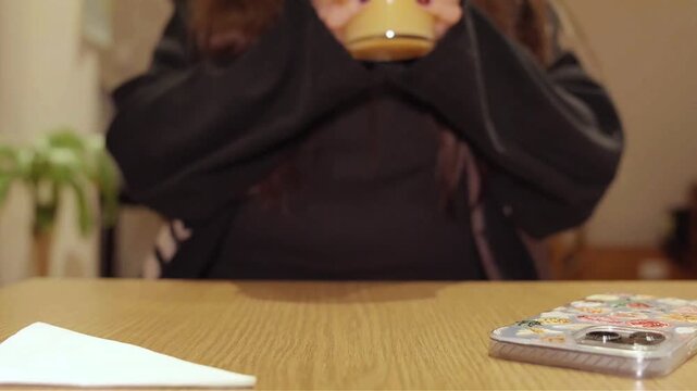 Primer plano de manos femeninas con u&ntilde;as de gel brillantes y anillos elegantes en un caf&eacute;.