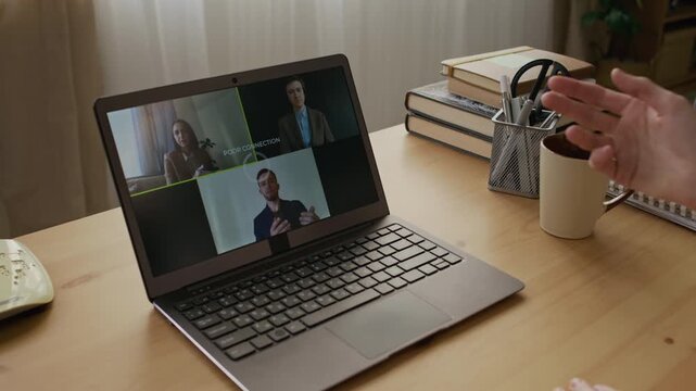 Over-shoulder shot of unrecognizable female employee discussing project with work colleagues during video call, losing connection, pressing buttons on laptop, using touchpad to restore internet link
