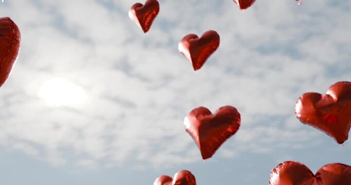 Red heart balloons floating in cloudy blue sky looping animation