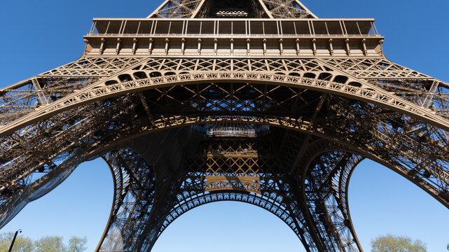 Dramatic low angle view of Eiffel Tower in Paris against deep blue sky, showcasing intricate iron structure and symmetry, iconic landmark, travel destination, architectural detail in France.