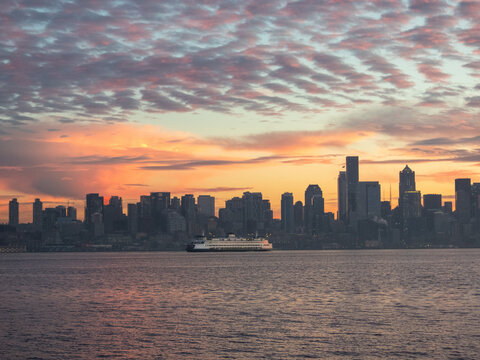 A commuter ferry passing the Seattle skyline in Elliott Bay at sunrise