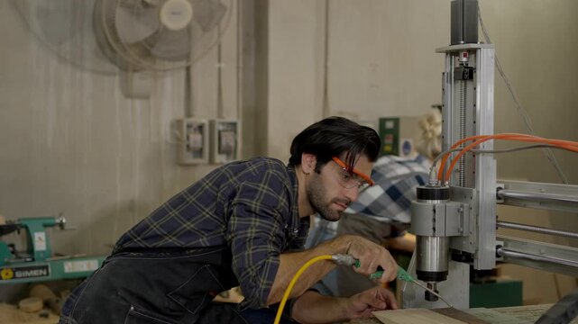 Man technician workshop wearing safety glasses operates machine drill press with cable tool factory industry, focused carpenter craftsmanship using woodworking equipment for precision manufacturing