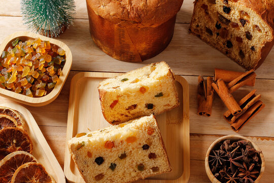 Traditional Christmas panettone with candied fruit and spices on a wooden table, with cinnamon and star anise