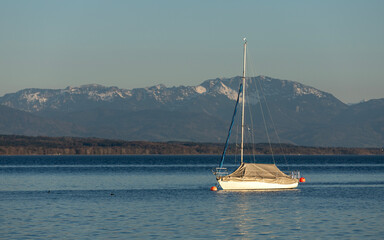 Moored sailboat on calm lake with mountain backdrop in Bavaria © Chanawat