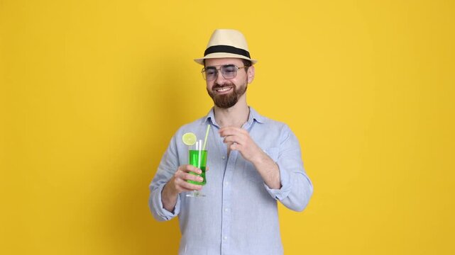 Handsome man in beachwear with cocktail on orange background