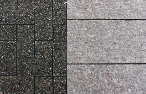Texture of wet grey interlocking brick and pink square paving tile after the rain. Pattern of sidewalk bricks and tiles in the street. Rainy concrete pavers close up background.