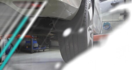Fototapeta premium Showing rear-right tire and coil spring mounting on silver car in garage, with red lift arm