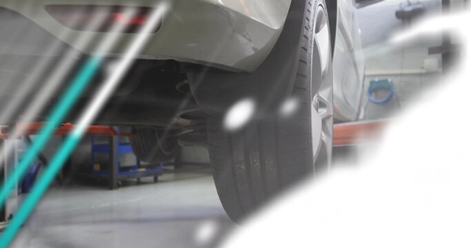 Showing rear-right tire and coil spring mounting on silver car in garage, with red lift arm