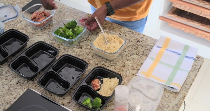 Man placing four meal boxes for lunches, scooping grain, adding protein and broccoli, copy space