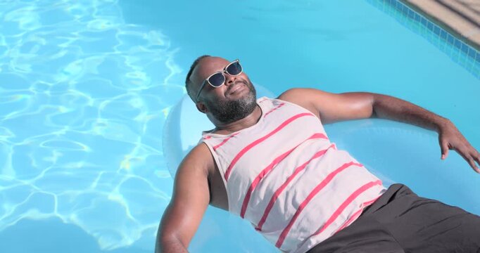 Vertical video: Camera panning, man bracing on float fixing shades in home pool, tank, copy space