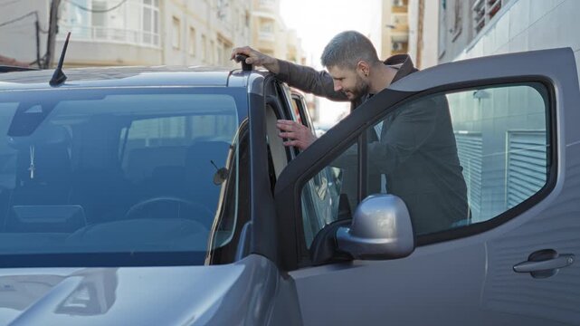 Man leans into car door with hand on roof and later gives thumb up by open driver door on narrow street lined with buildings; confidence reassurance.