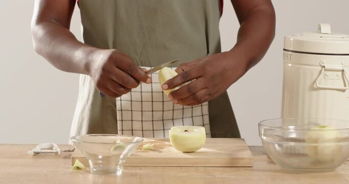 Paring knife is removing core from apple half, slicing wedges and dicing on kitchen counter