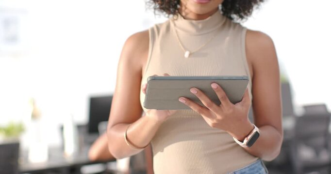 Female in tan top holding folio tablet at office after receiving message, tapping and smiling