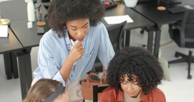 Vertical video: Leaning woman in blue top leading team in office using laptop and docs editing deck