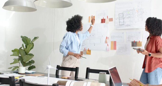 Vertical video: Reaching presenter arranging and pointing swatches on office wall, seeking feedback