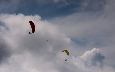 Parapentistas volando entre nubes en un cielo dramático © Manuela