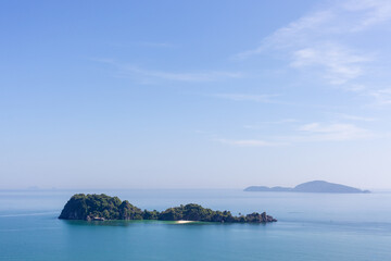 Gulf of Thailand's islands near Chumphon. Turquoise waters surround lush, green islands under a clear blue sky. Distant landmasses visible on horizon.