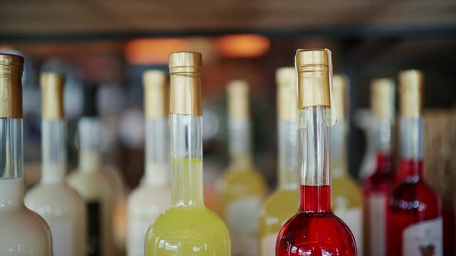Close up of colorful liqueur bottles with yellow and red liquids on a bar counter