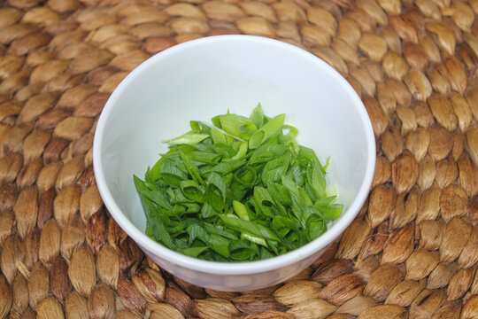 Chopped Green Onions in White Bowl on Woven Mat