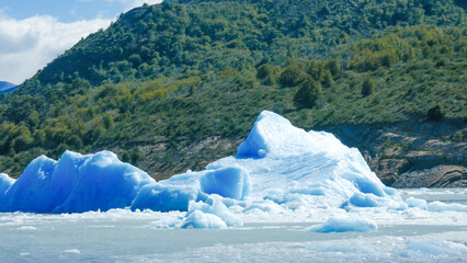 Floating blue icebergs in cold glacial water, natural polar landscape with frozen ice formations and calm surface © Daryna