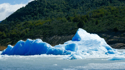 Floating blue icebergs in cold glacial water, natural polar landscape with frozen ice formations and calm surface © Daryna