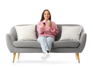 Obraz premium Young woman with cup of tea watching TV on grey couch against white background
