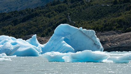 Floating blue icebergs in cold glacial water, natural polar landscape with frozen ice formations and calm surface © Daryna