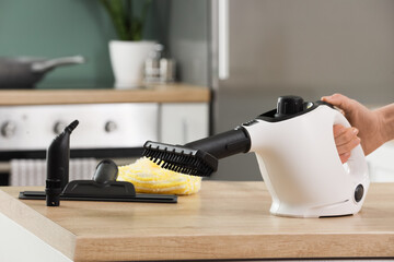 Female hand with steam cleaner on counter in kitchen