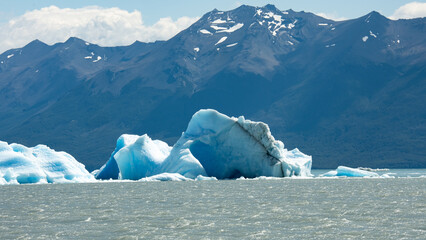 Floating blue icebergs in cold glacial water, natural polar landscape with frozen ice formations and calm surface © Daryna