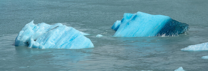 Floating blue icebergs in cold glacial water, natural polar landscape with frozen ice formations and calm surface © Daryna