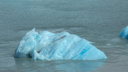 Floating blue icebergs in cold glacial water, natural polar landscape with frozen ice formations and calm surface © Daryna