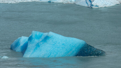 Floating blue icebergs in cold glacial water, natural polar landscape with frozen ice formations and calm surface © Daryna