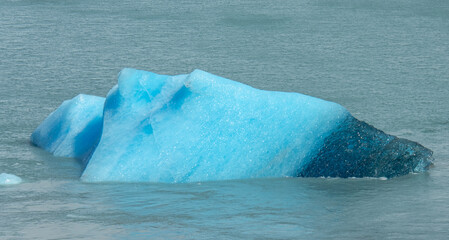 Floating blue icebergs in cold glacial water, natural polar landscape with frozen ice formations and calm surface © Daryna