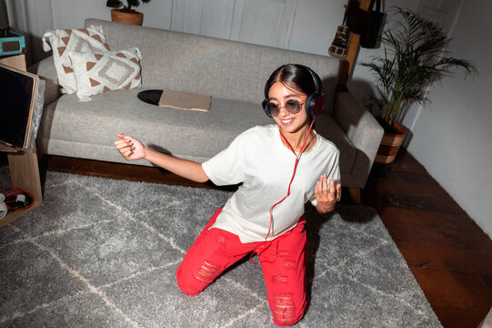 Young woman enjoying music dancing in living room