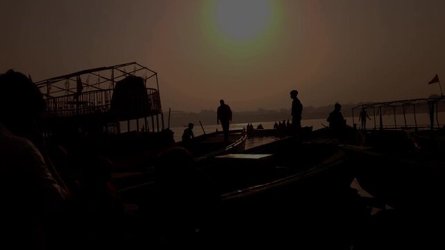 Silhouettes of People and Wooden Boats at Riverside During Sunrise, Golden Hour Reflection on Calm Water, Scenic Travel Landscape