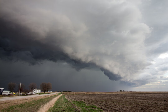 A dark storm approaches over rural farmland.