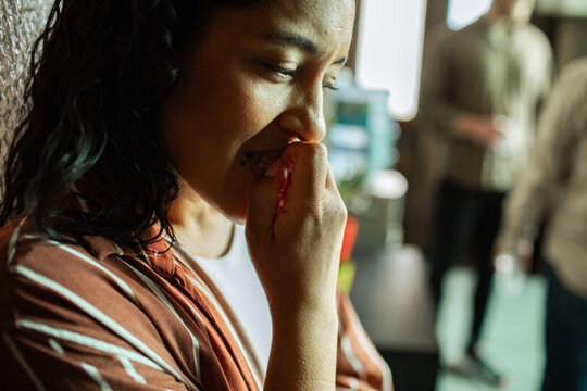 Anxious young woman biting nails in office