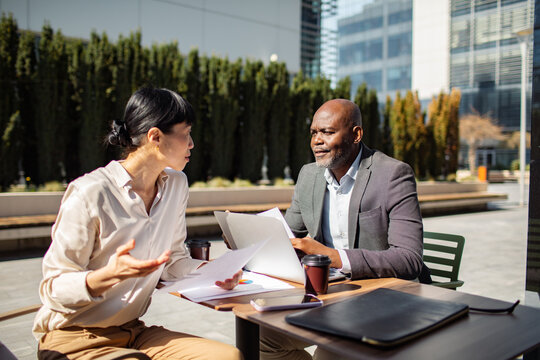 Two business colleagues reviewing reports in an outdoor office courtyard